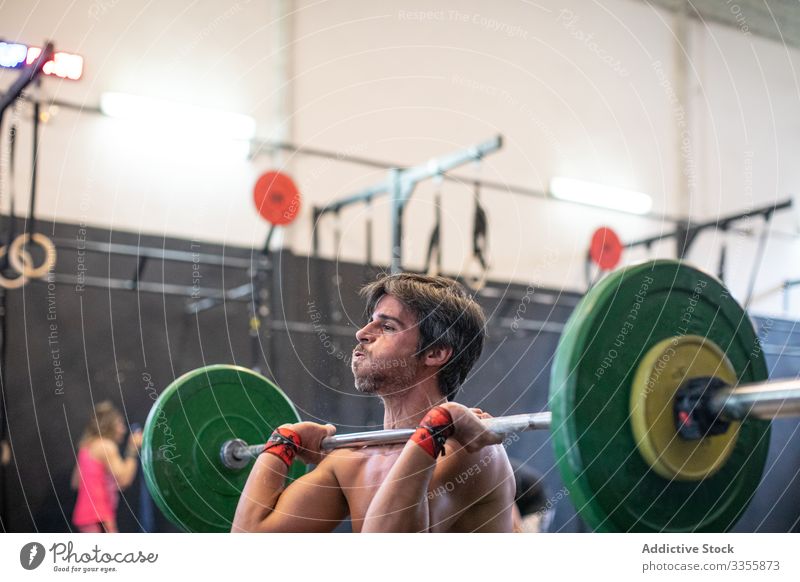 Muskulöser Mann hebt Langhantel im modernen Fitnessstudio Sportler Training Gewichtheben Curl-Hantel schwer anstrengen Erwachsener stark männlich angespannt