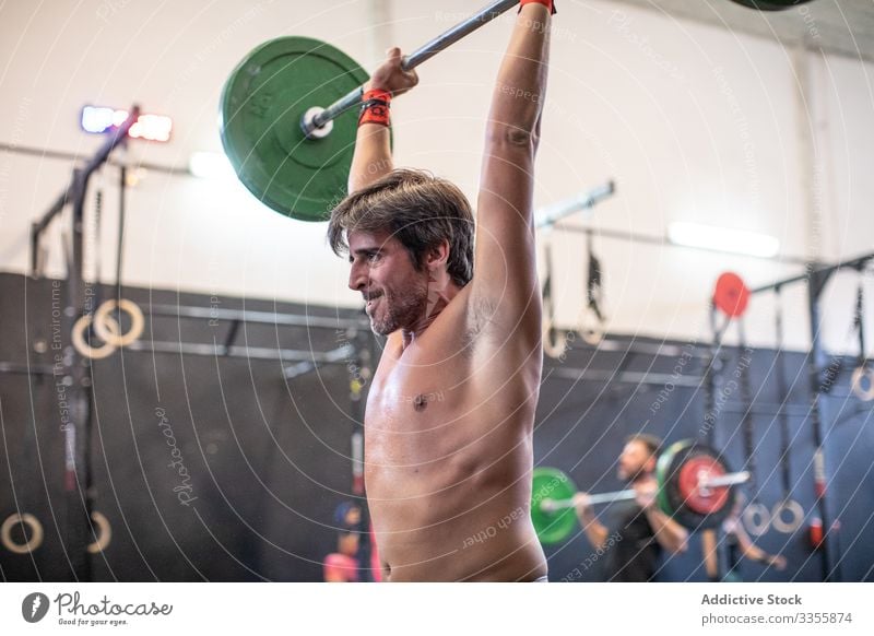 Muskulöser Mann hebt Langhantel im modernen Fitnessstudio Sportler Training Gewichtheben Curl-Hantel schwer anstrengen Erwachsener stark männlich angespannt