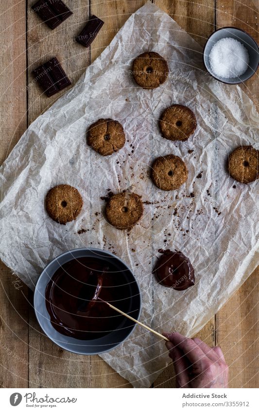 Cook gießt gebackene Kekse mit Schokoladensirup auf Backpapier Koch Gießen Sirup Bäckerei Lebensmittel selbstgemacht Essen zubereiten Vorbereitung Kuchen Küche