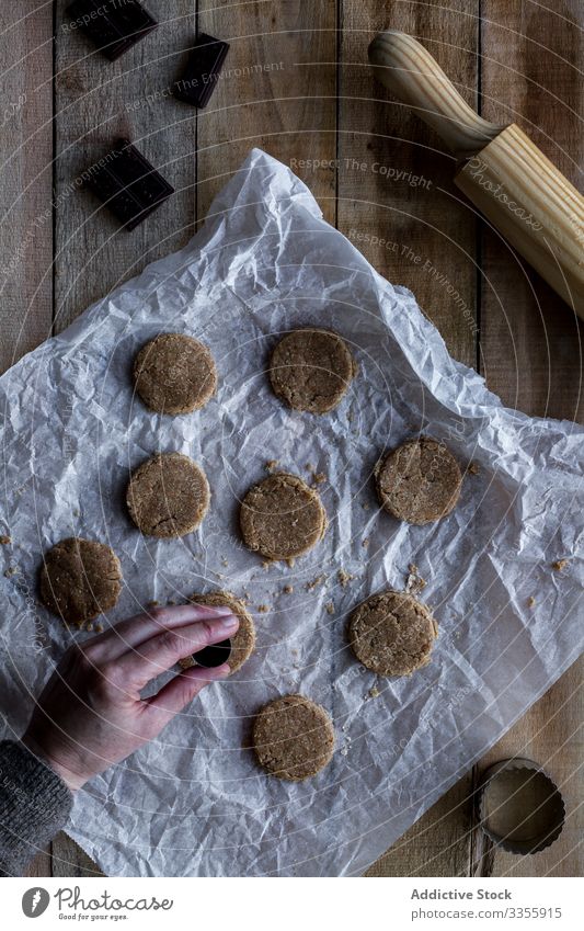 Koch hält Schokoladenteig in der Hand auf Backpapier Teigwaren Mehl Nudelholz Kochform Metall Bäckerei Lebensmittel selbstgemacht Essen zubereiten Vorbereitung