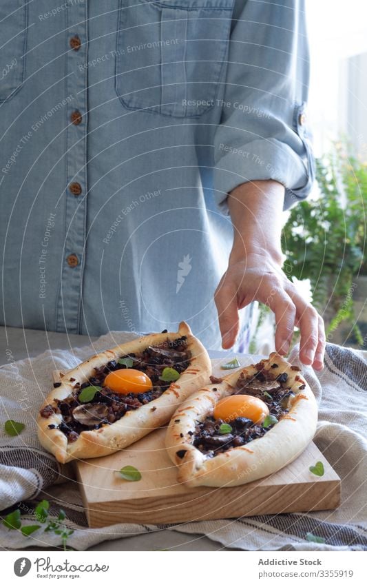 Person, die frisch zubereitete kachapuri auf Tisch auf Holzständer serviert Ei geschmackvoll appetitlich Mahlzeit Speise Abendessen Lebensmittel Mittagessen