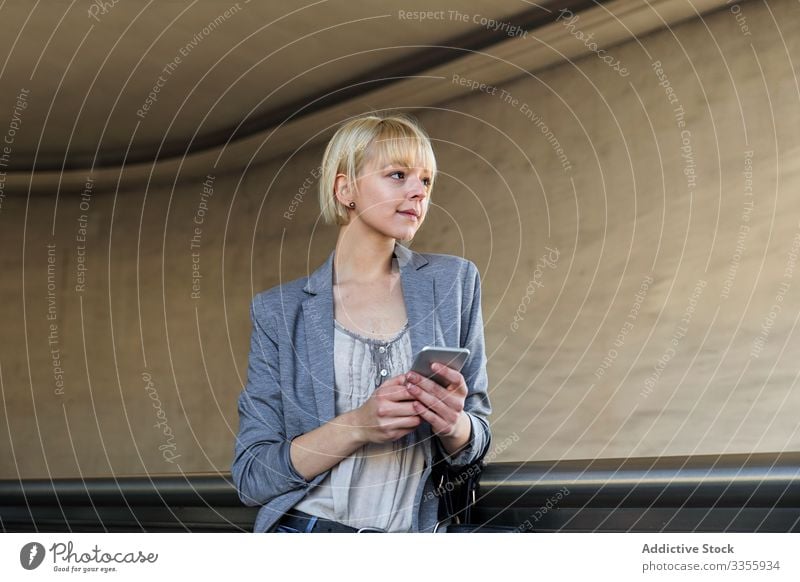 Lächelnde Geschäftsfrau mit Smartphone stylisch jung heiter Geländer Lehnen Frau professionell Person schön benutzend Browsen attraktiv Unternehmer elegant