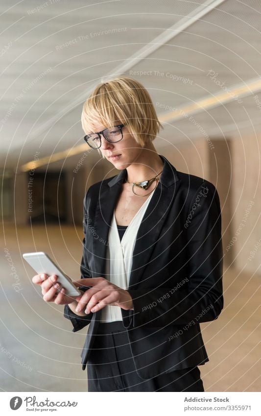 Stilvolle Geschäftsfrau surft auf Smartphone Telefon Mobile Anschluss Browsen zuschauend stylisch jung Frau selbstbewusst Saal professionell Person schön