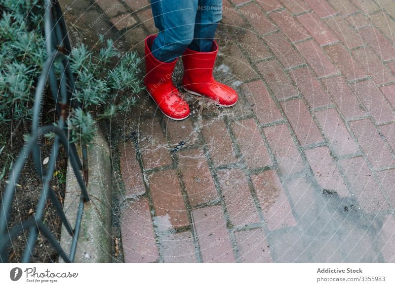 Aktives Kind springt in Pfütze in Parkallee springend unordentlich Saison lustig Wasser nass Schmutz Kindheit Wetter Schlamm Herbst Spiel aktiv Gummistiefel