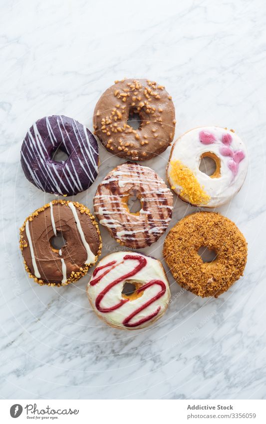 Verschiedene Doughnuts auf Marmor-Hintergrund Varieté Sortiment süß Zuckerguß verglast Lebensmittel Krapfen Bäckerei Gebäck bestäuben gebraten farbenfroh viele