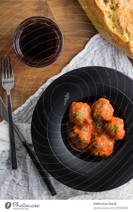 Köstliche Frikadellen auf rustikalem Tisch serviert Fleischklößchen Tomatensauce Brot Getränk Besteck Teller lecker Lebensmittel Mahlzeit selbstgemacht