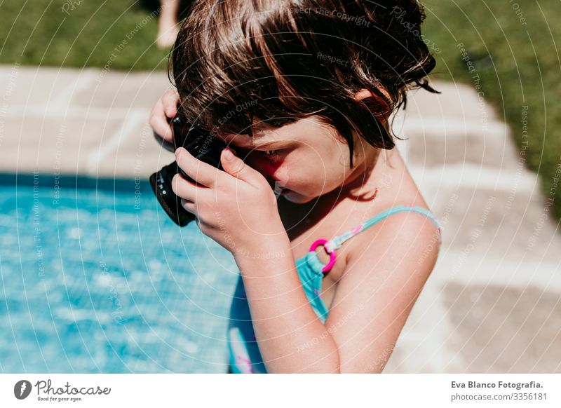 Hübsches Mädchen, das mit einer alten Oldtimer-Kamera in einem Pool fotografiert. Lächelnd. Spaß und sommerlicher Lebensstil Aktion Schwimmbad Beautyfotografie