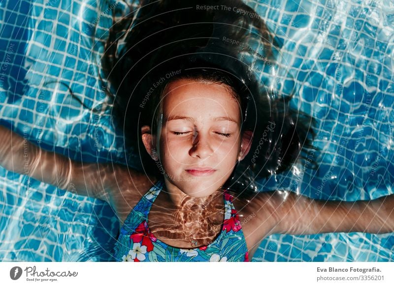 Ein wunderschöner Teenager schwebt in einem Pool und schaut in die Kamera. Spaß und sommerlicher Lebensstil Aktion Schwimmbad Beautyfotografie Außenaufnahme