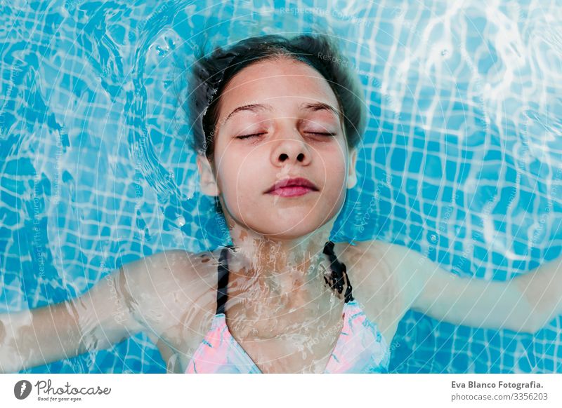 Ein wunderschöner Teenager schwebt in einem Pool und schaut in die Kamera. Spaß und sommerlicher Lebensstil Aktion Schwimmbad Beautyfotografie Außenaufnahme