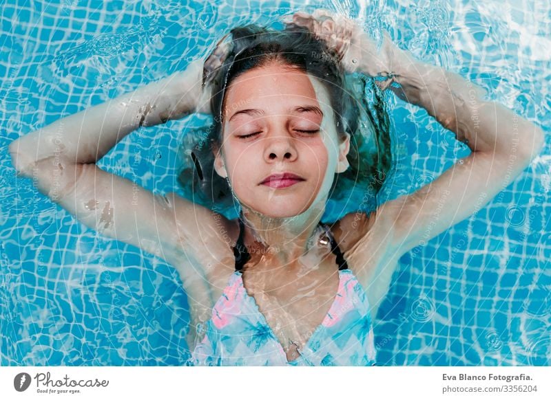 Ein wunderschöner Teenager schwebt in einem Pool und schaut in die Kamera. Spaß und sommerlicher Lebensstil Aktion Schwimmbad Beautyfotografie Außenaufnahme