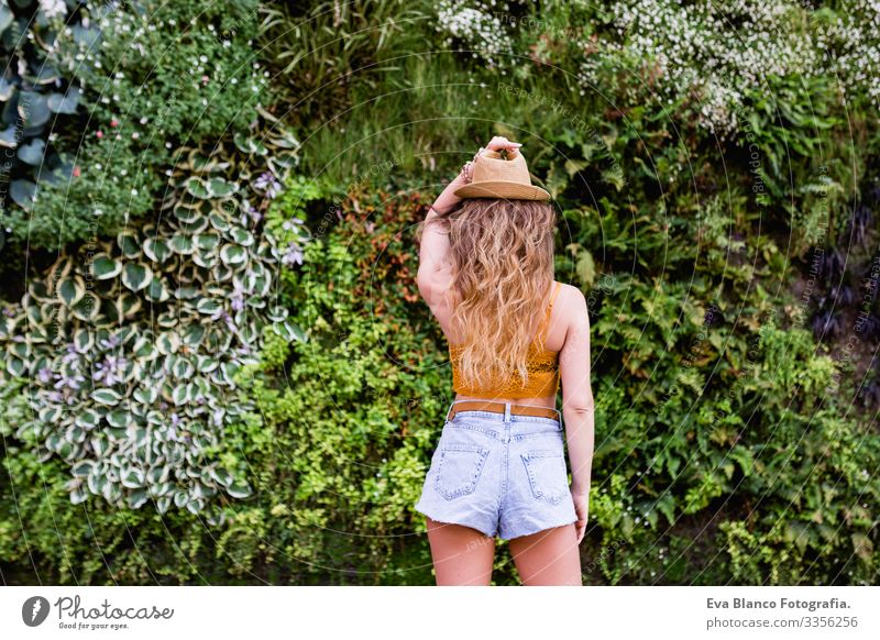 Porträt einer jungen, blonden, schönen Frau auf der Straße, die lächelt. Grüner Vegetationshintergrund. Lebensstil im Freien. Sommerzeit modern trendy Erotik