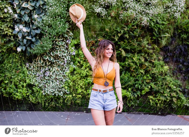 Porträt einer jungen, blonden, schönen Frau auf der Straße, die lächelt. Grüner Vegetationshintergrund. Lebensstil im Freien. Sommerzeit modern trendy Erotik