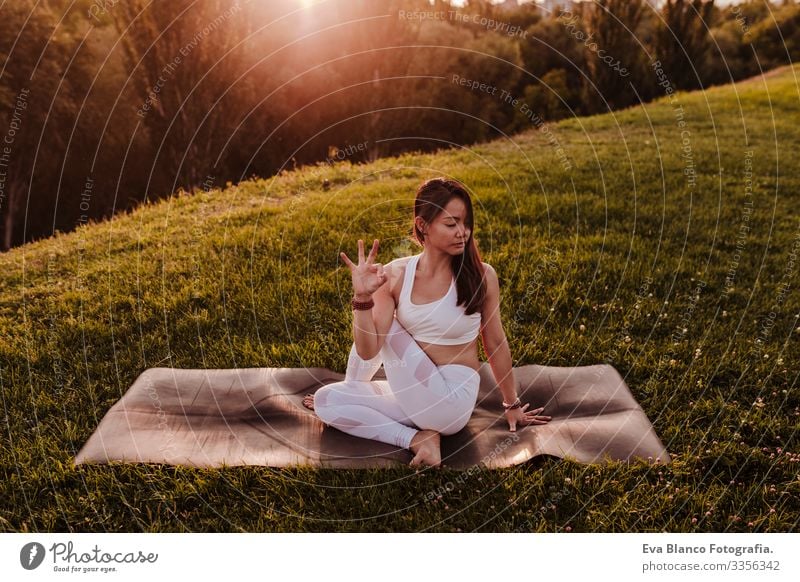 junge schöne asiatische Frau, die bei Sonnenuntergang in einem Park Yoga macht. Konzept für Yoga und gesunde Lebensweise Jugendliche Sommer Glück Genuss Sport