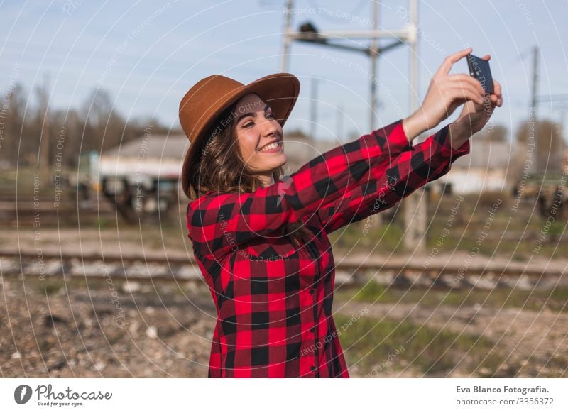 junge schöne Frau in Freizeitkleidung, Outdoor-Lifestyle. Städtischer Hintergrund. Sie macht ein Foto oder einen Selfie mit dem Handy und lächelt. Großstadt