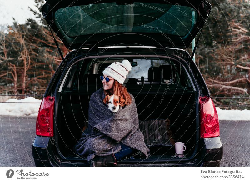 Frau und süßer Jack Russell Hund genießen draußen am Berg in das Auto. Reisekonzept. Wintersaison PKW Schnee Berge u. Gebirge Außenaufnahme