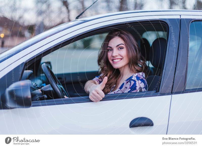 Junge Frau, die in der Stadt Auto fährt. Porträt einer schönen Frau in einem Auto, die aus dem Fenster schaut und lächelt. Reise- und Urlaubskonzepte