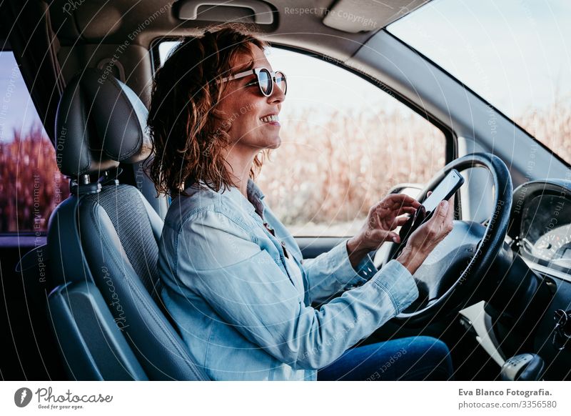 junge, schöne Frau, die im Auto mobil telefoniert. reisekonzept Handy Technik & Technologie benutzend Jugendliche fahren PKW Sonnenstrahlen Sonnenbrille