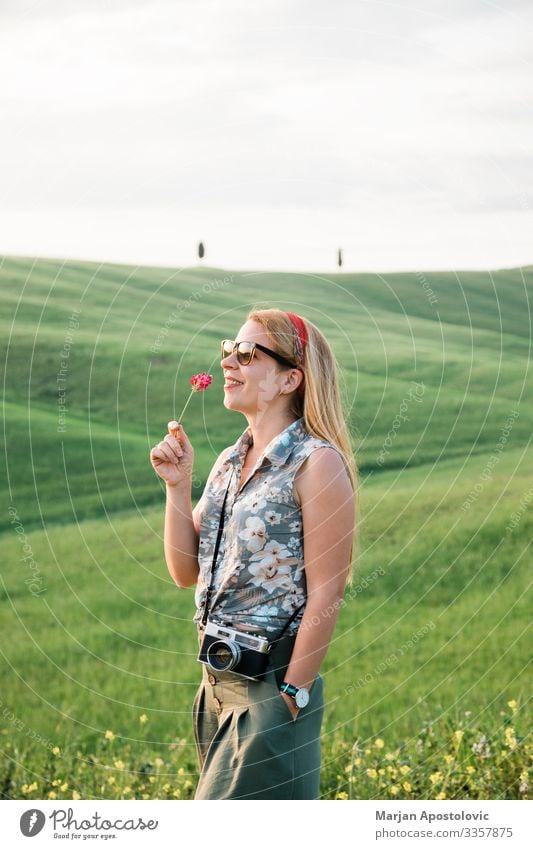 Junge Frau riecht an einer Blume in einer schönen toskanischen Landschaft Lifestyle Freude harmonisch Ferien & Urlaub & Reisen Tourismus Ausflug Abenteuer