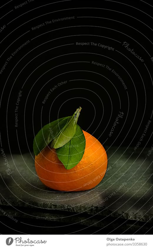 reife, saftige Mandarine mit grünem Blatt auf schwarzem Grund Clementine Vegetarische Ernährung süß organisch Gesunde Ernährung Frucht tropisch frisch Zirkus