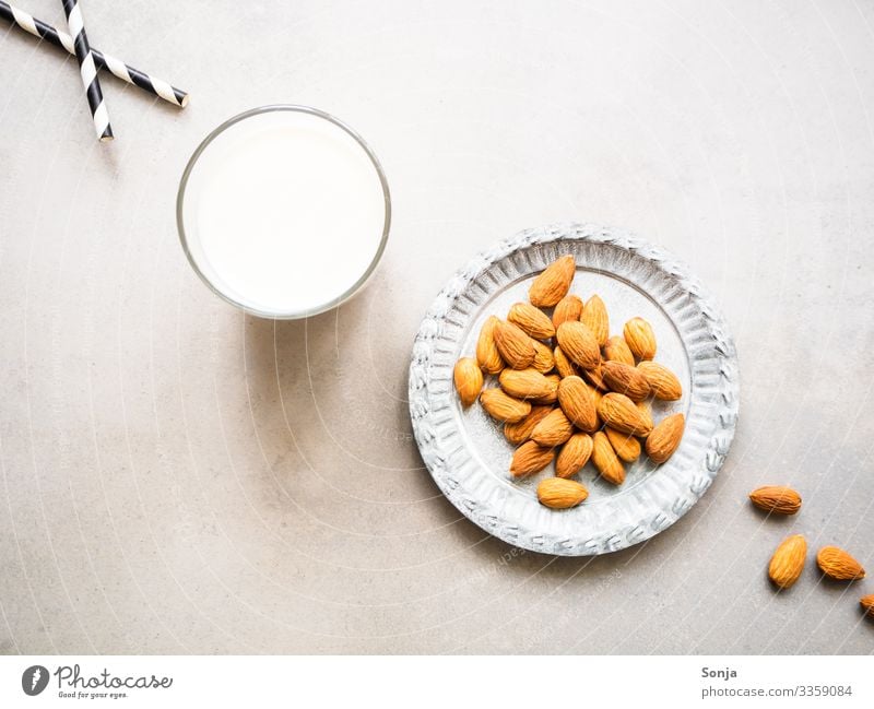 Ein Glas Mandelmilch und ein Teller mit Mandeln Lebensmittel Milcherzeugnisse Ernährung Frühstück Bioprodukte Vegetarische Ernährung Diät Getränk Trinkhalm