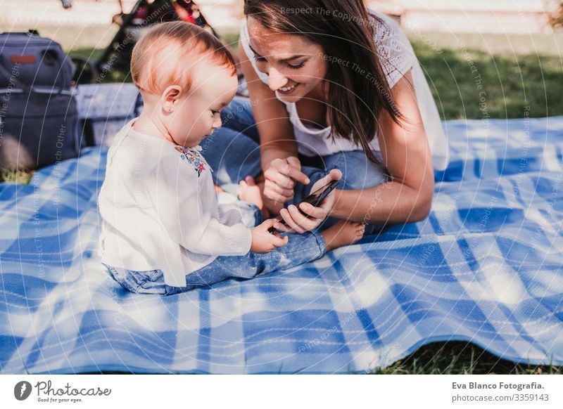 junge Mutter und glückliches Baby, das im Freien mit dem Handy telefoniert. technologiekonzept Technik & Technologie Zusammensein Kind Kindererziehung Mädchen