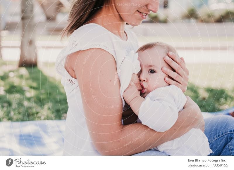 junge Mutter, die im Park im Freien ihr Baby stillt, glückliches Familienkonzept. liebe Mutter-Tochter stillen Milch Essen Kind Kindererziehung Mädchen Freude