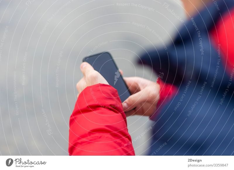 Junger Mann mit einem Smartphone in der Hand schreibt draußen auf der Straße SMS Mobile Beteiligung benutzend Telefon Technik & Technologie Handy Gerät