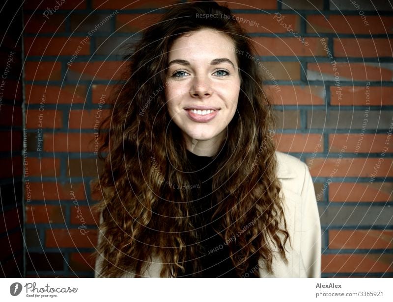 Portrait einer jungen Frau vor einer Ziegelsteinwand Lifestyle Stil Freude schön Leben Junge Frau Jugendliche Gesicht 18-30 Jahre Erwachsene Mantel brünett