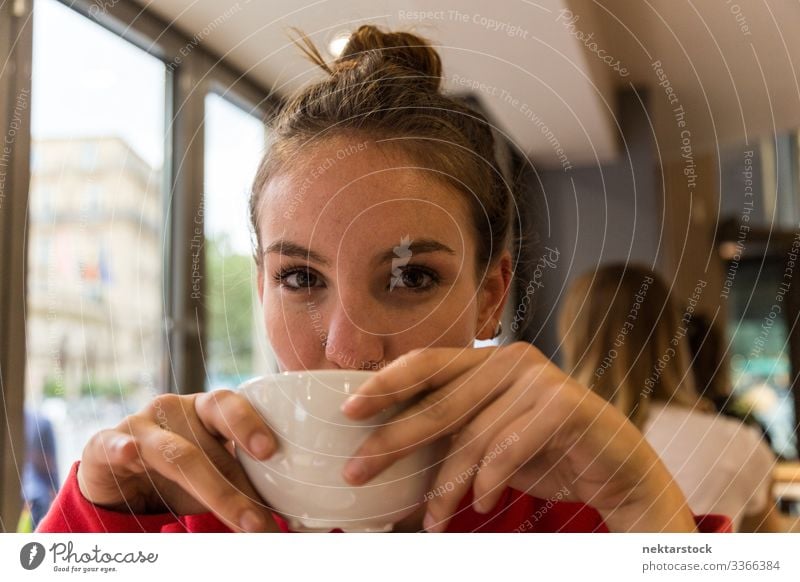 Junge Frau trinkt aus Kaffeetasse und schaut in die Kamera Mädchen junger Erwachsener Gesicht Tag weibliche Schönheit schöne Frau natürliche Schönheit 1 Mensch