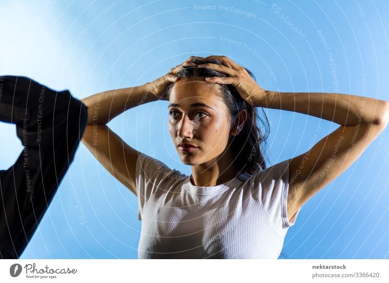 Junge Frau mit Händen auf dem Kopf im Studio mit blauem Hintergrund Hände auf dem Kopf Mädchen junger Erwachsener weibliche Schönheit schöne Frau