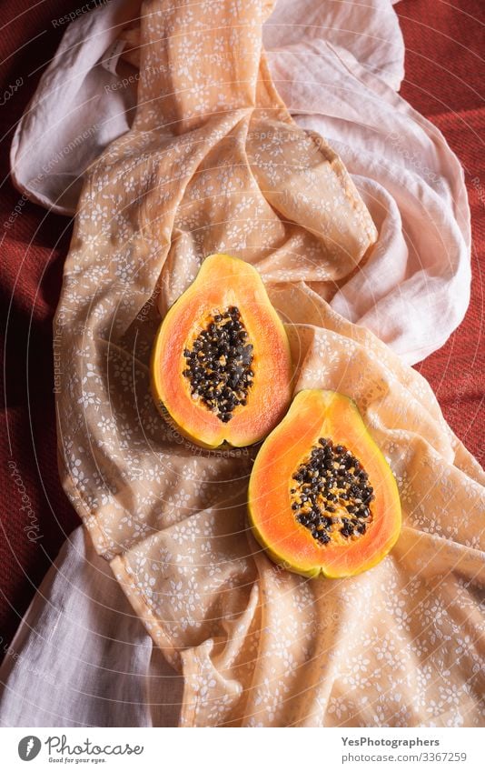 Reife Papayafruchthälften auf orangefarbenen Tischdecken. Frucht Dessert Bioprodukte exotisch Gesunde Ernährung obere Ansicht farbenfroh halbieren Diätnahrung