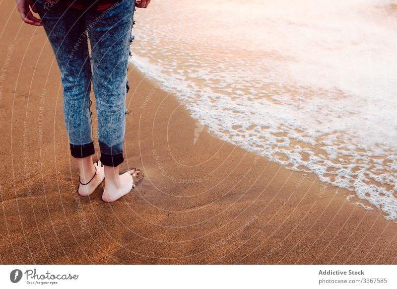 Frau in Jeans am Strand stehend Barfuß Hipster Jeanshose MEER Sand stürmisch anhaben Stil Persönlichkeit Meer Wasser Natur reisen Küste Seeküste Umwelt einsam