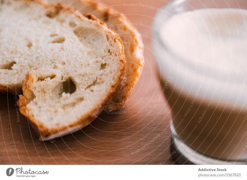 Latte im durchsichtigen Glasbecher mit Brotscheiben Kaffee melken Tasse mischen Morgen Tisch trinken Getränk Frühstück Cappuccino Koffein frisch Aroma Energie