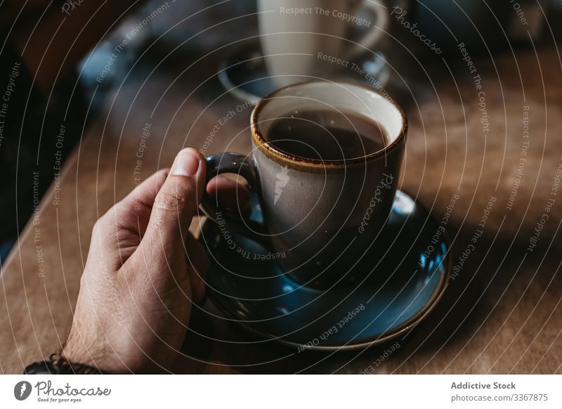 Anonyme Frau mit Kaffeetasse im Café Tasse Hand Erwachsener Person Sitzen genießend frisch heiß gebraut Becher trinken Getränk schwarz Tisch hölzern Kantine