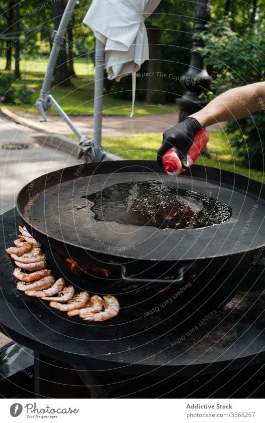 Männlicher Erntehelfer gießt Öl auf Pfanne Mann eingießen Erdöl Koch Speise Küchenchef Granele Ofen Paella gebraten männlich heiß Marktplatz Vorbereitung