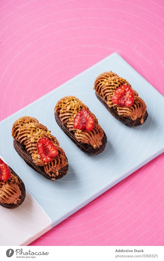 Schokoladen-Eclairs mit frischen Himbeeren Dessert eclair süß Karamell Sahne Holzplatte farbenfroh hell Lebensmittel Gebäck geschmackvoll Küche Speise lecker