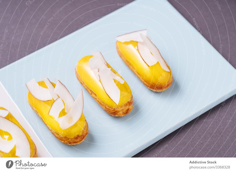 Leckere Eclairs mit Kokosnuss Dessert eclair Frucht Banane Zuckerguß süß Holzplatte Lebensmittel Gebäck geschmackvoll Küche Speise lecker Kalorie Portion