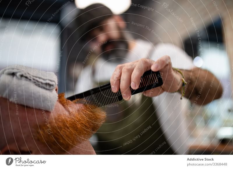 Anonymer Barbier stutzt rothaarigen Herrenbart Männer Klient trendy Friseur Barbershop Vollbart Maskulinität Kunde Pflege Salon gutaussehend stylisch