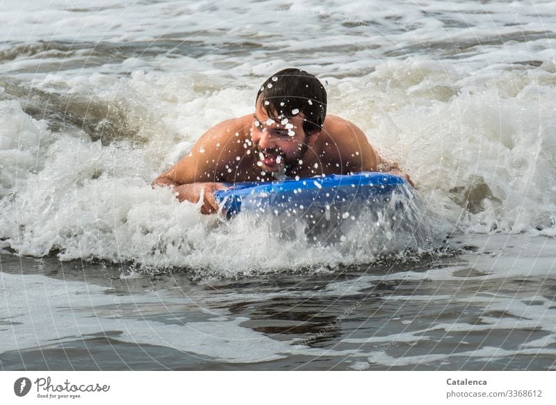 Spaß beim baden im Meer Person männlich junger Mann schwimmen wellenreiten Board Brandung Gischt nass Strand Sommer Blau Grau Freude Ferien Wasser