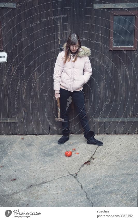 fotochallenge: jugendliche betrachtet eine matschige überreife tomate und überlegt diese mit einem hammer zu zerkleinern Fotochallenge Jugendliche Teenager