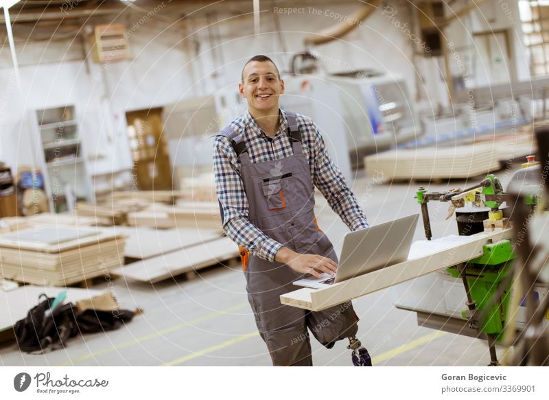 Behinderter junger Mann mit einer Beinprothese, der in einer Fabrik arbeitet Möbel Arbeit & Erwerbstätigkeit Beruf Handwerker Arbeitsplatz Industrie Business