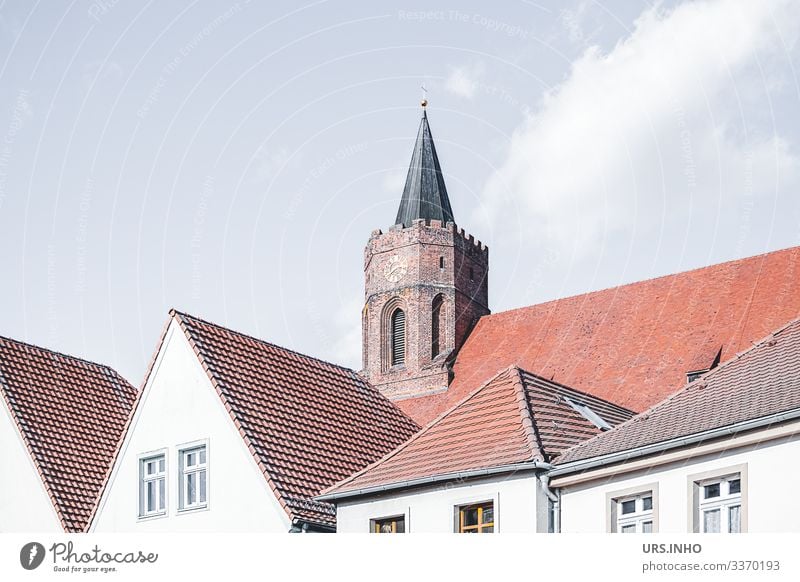 Kirchturm hinter Häuserdächern Beeskow Deutschland Europa Kleinstadt Menschenleer Haus Kirche Fenster Dach Turm Satteldach Walmdach oben Spitze blau braun