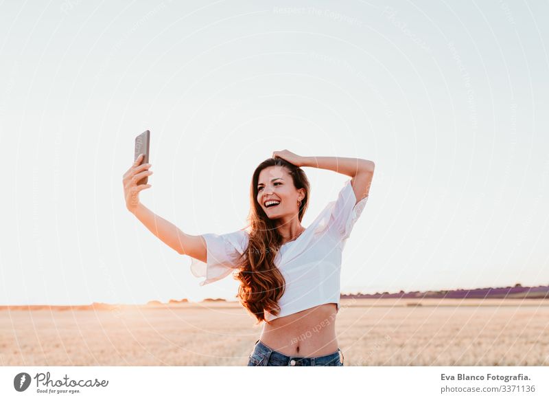 junge schöne frau auf dem land bei sonnenuntergang mit dem handy. technologiekonzept Handy Technik & Technologie Porträt Frau Sonnenuntergang im Freien