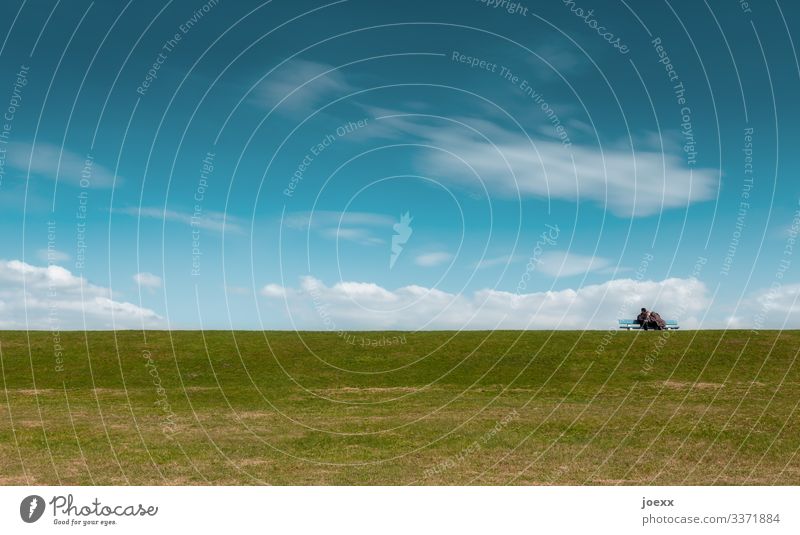 Pärchen Arm in Arm auf Parkbank mit grüner Wiese und blauem Himmel Wolken Schönes Wetter alt ruhig Fernweh Horizont Idylle Farbfoto Außenaufnahme Tag Weitwinkel