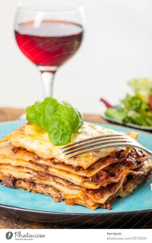 Lasagne auf einem blauen Teller Fleisch Käse Ernährung Mittagessen Abendessen Geschirr Restaurant Gastronomie Holz frisch Portion backen Spezialitäten Parmesan