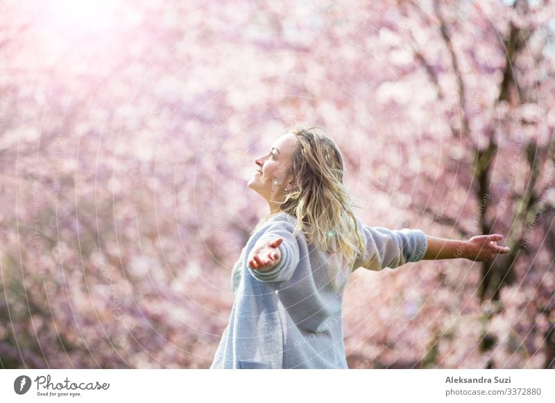 Junge Frau genießt die Natur im Frühling. Tanzen, laufen und wirbeln in schönen Park mit Kirschbäumen in der Blüte. Glück Konzept Beautyfotografie Körperpflege