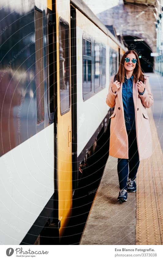 eine glückliche junge Frau, die am Bahnhof spazieren geht. Reisekonzept Bildschirm Ausflugsziel reisen Rucksack Kaukasier Europa Eisenbahn Warten Wagen Schiene