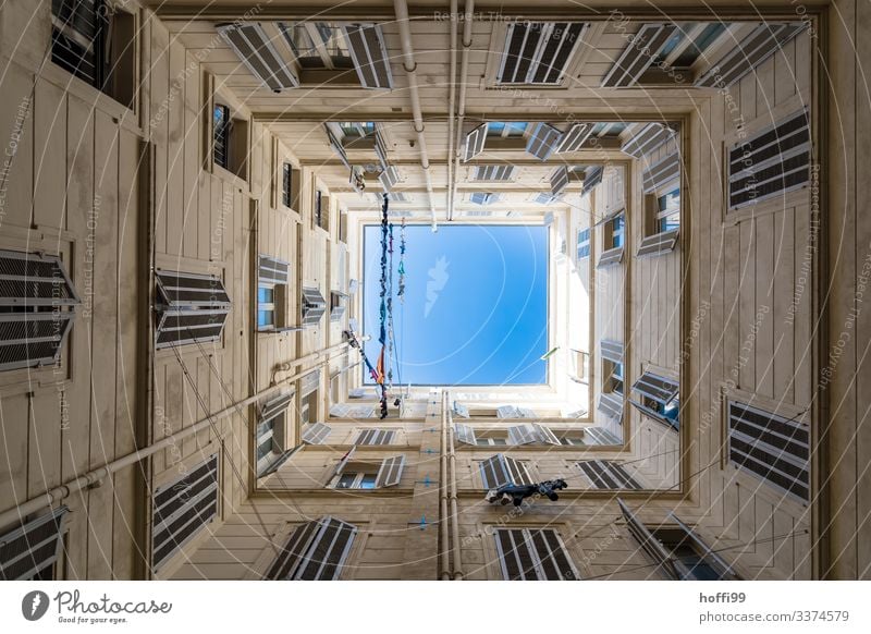 Blick nach oben in einem quadratischen Innenhof mit Wäscheleinen und tiefblauem Himmel Schönes Wetter Haus Mauer Wand Fassade Fenster Fensterladen