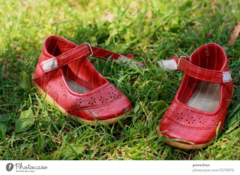 Rote Kinderschuhe im Gras Schuhe ballerinas rot sommerschuhe geöffnet klettverschluss ausziehen gras grün komplementärfarben barfuß wiese freude Rasen