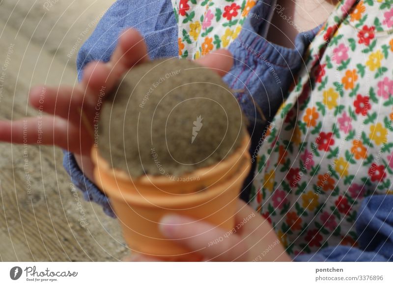 Kinderhände formen eine Eiskugel aus Sand Kleinkind sand spielen freude sandkasten spielplatz muster eis eiswaffel sandförmchen Sommer Farbfoto Außenaufnahme